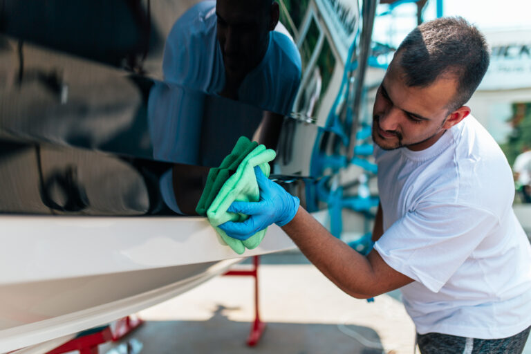 Boat maintenance - A man cleaning boat with cloth.