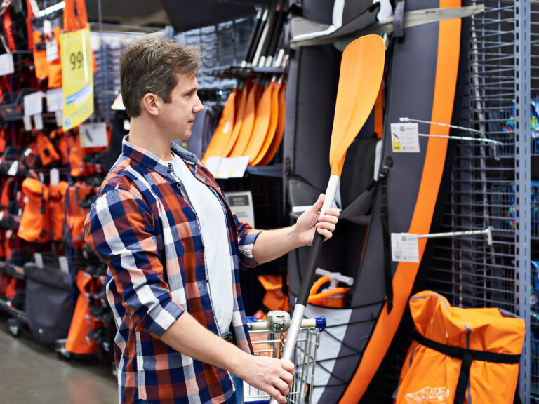 Man with paddle for sport boat kayak in store